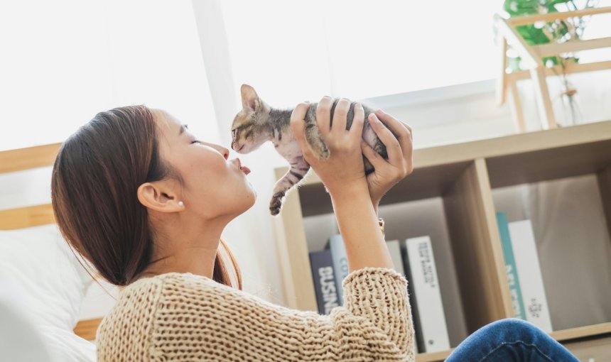 A woman kissing a small cat