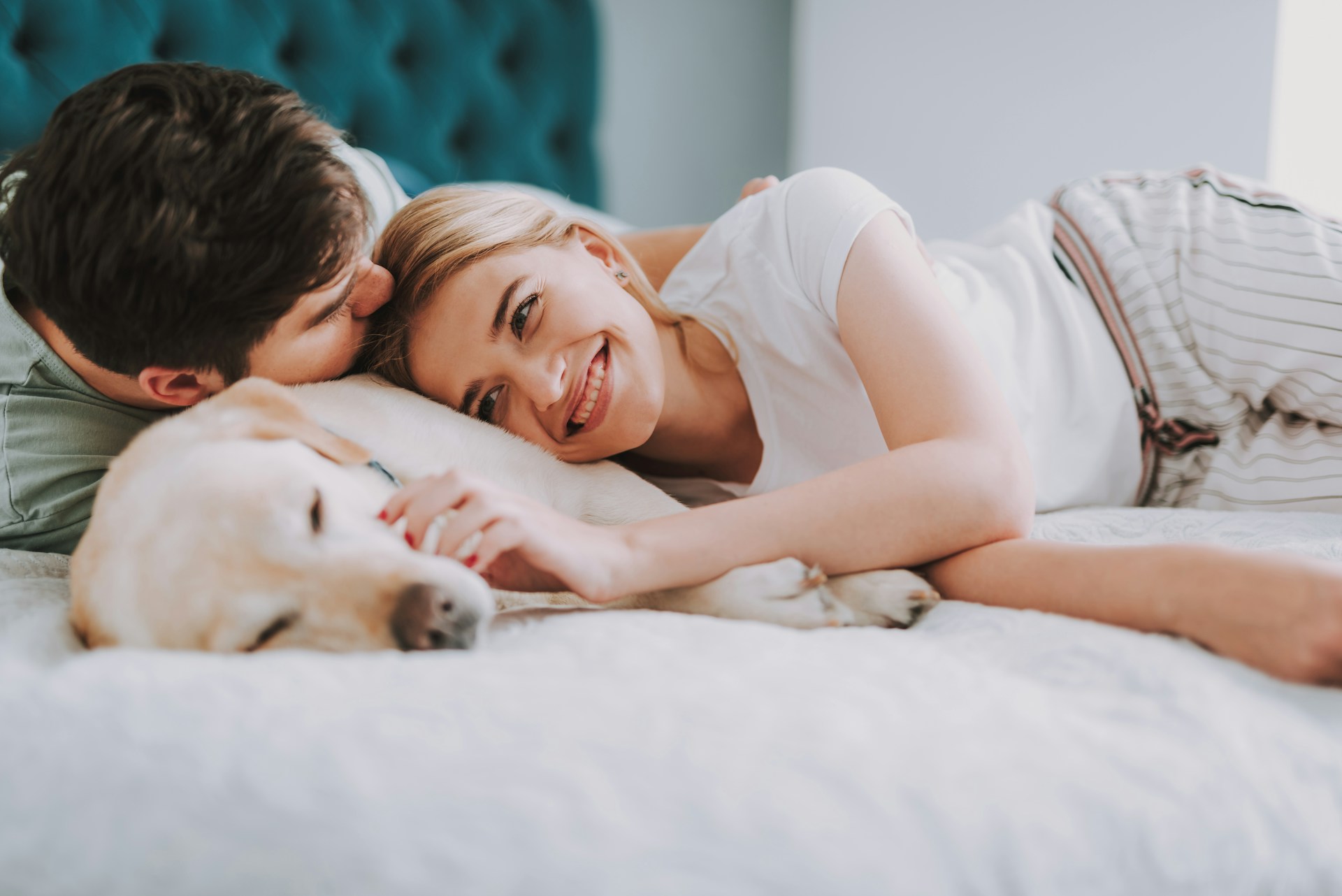 A couple lying in bed next to a dog