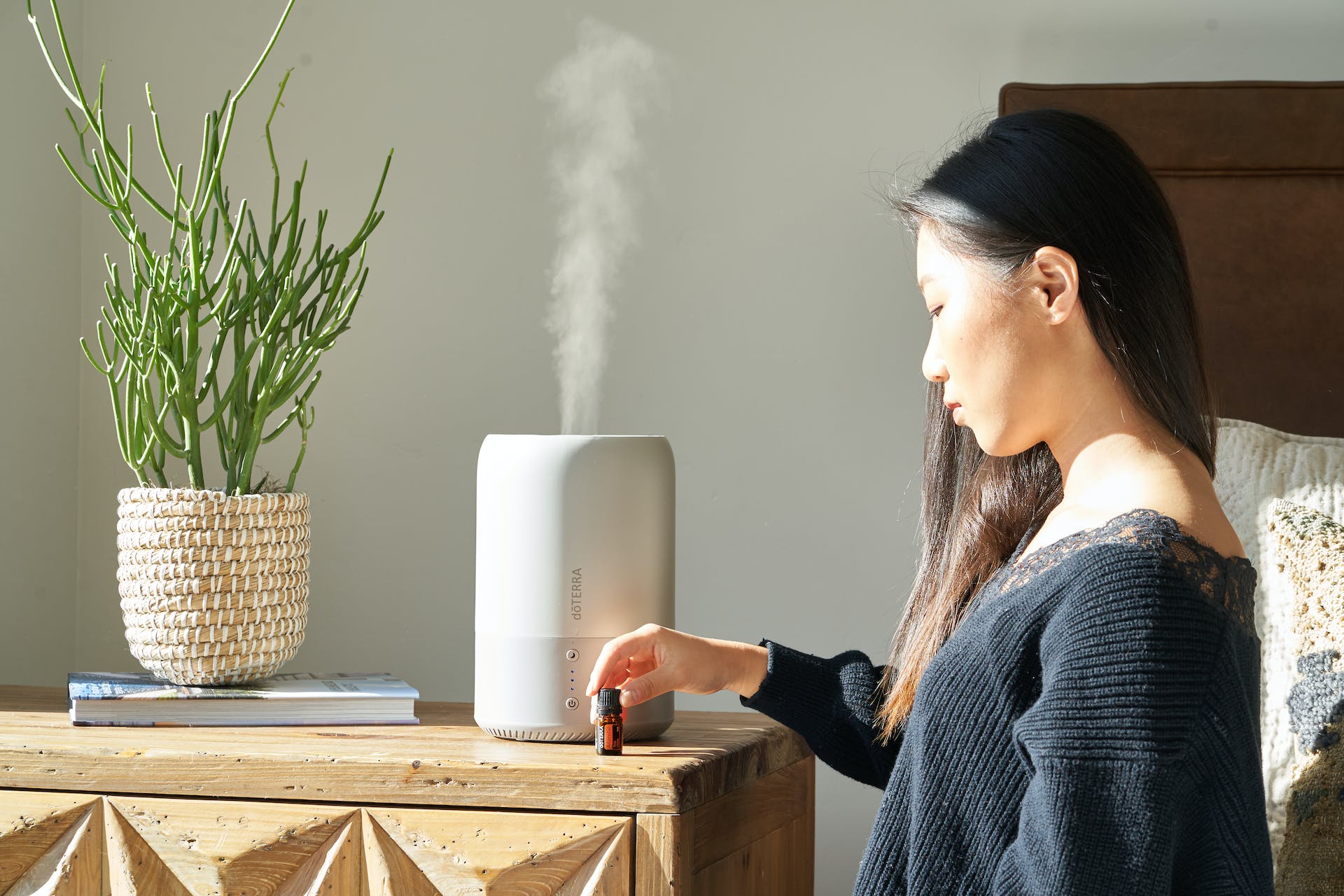 A woman setting up a humidifier in a bedroom
