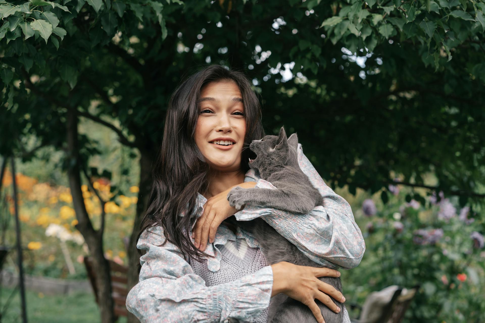 A woman holding a cat in her arms outdoors