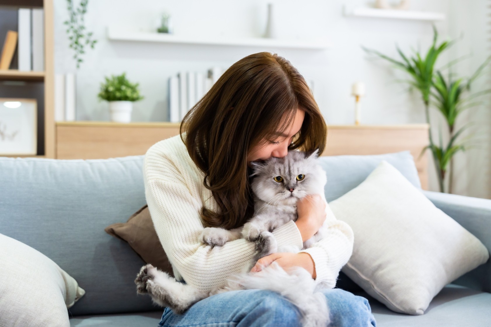 A woman hugging a cat on a couch