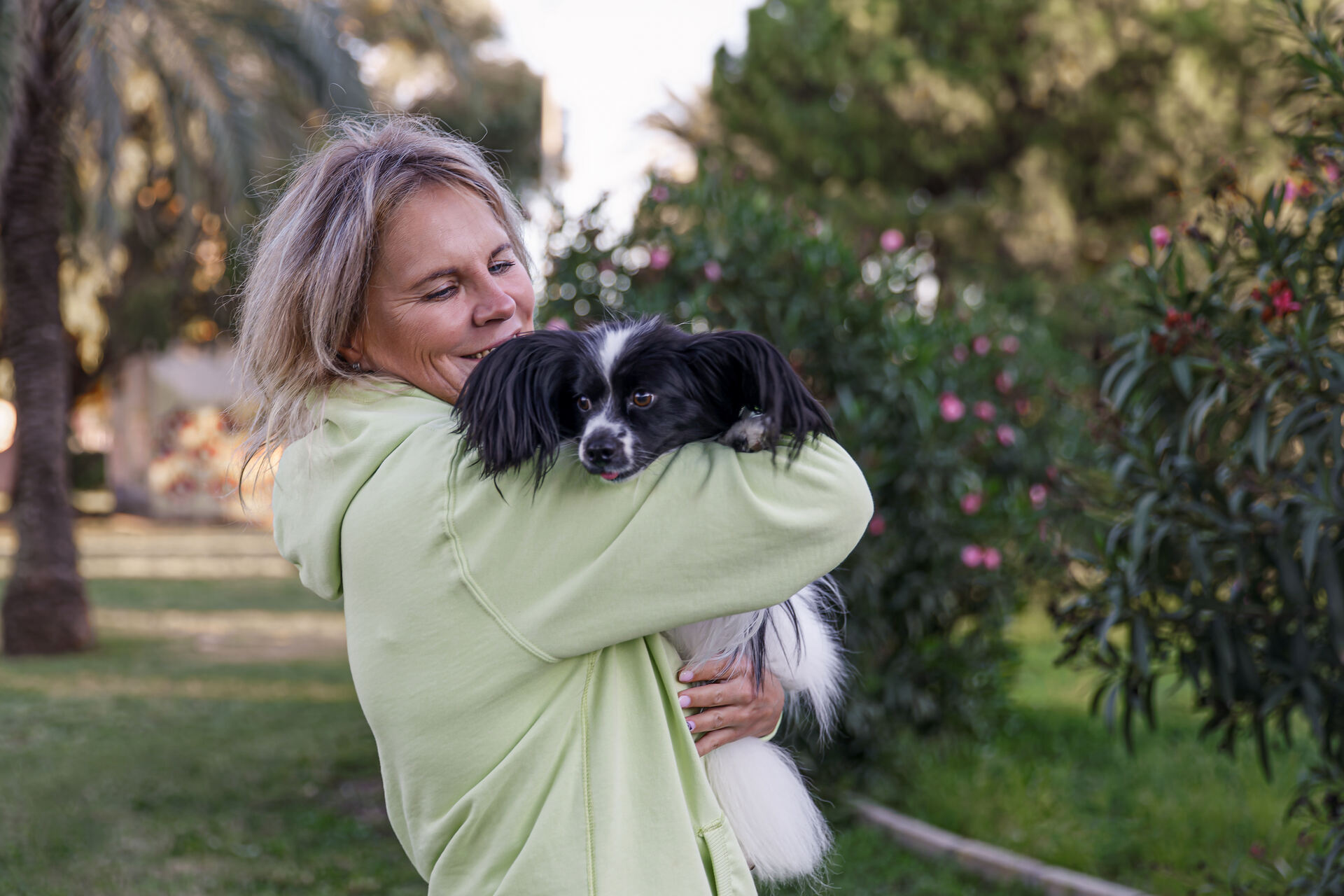 A woman hugging a small dog at a park