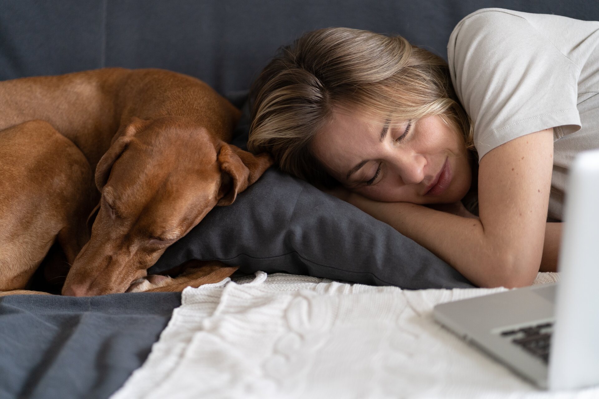 A woman and dog sleeping together on a couch