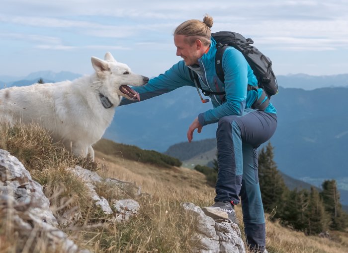 A man hiking with a white dog