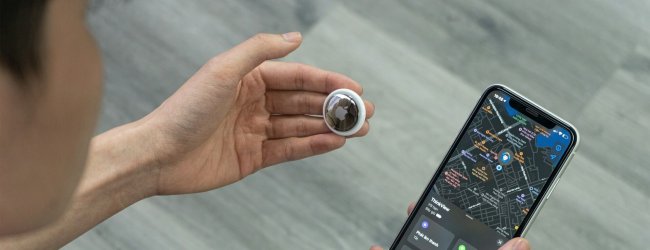 Close up of a person's hands holding an Apple AirTag tracker in one and a smartphone with map screen in the other