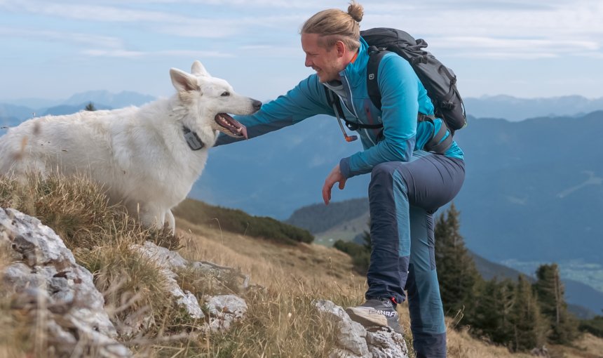 Hundebesitzer streichelt seinen Hund mit Tractive GPS Tracker am Berggipfel