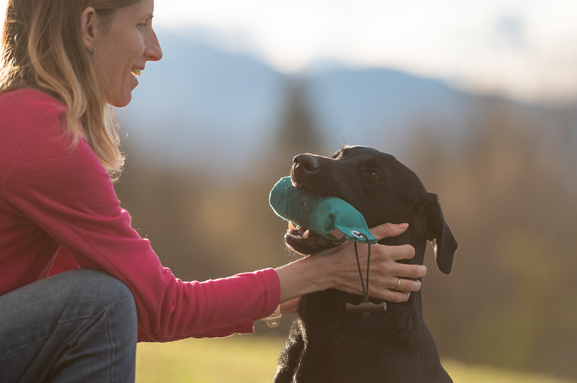 A woman using a toy to train a deaf dog to be quiet