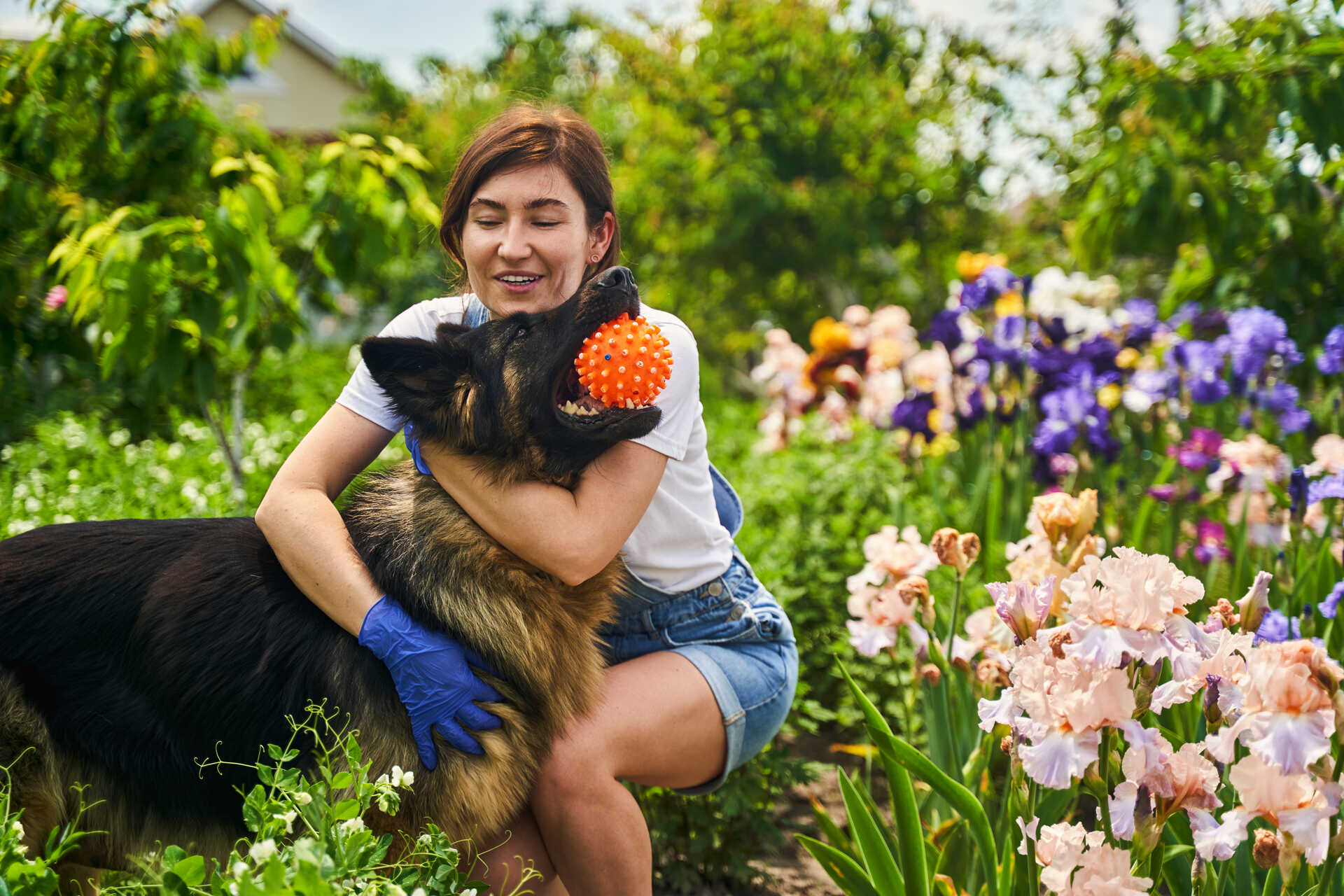 A woman hugging her dog while gardening