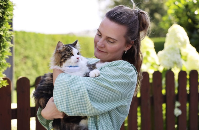 A woman holding a cat wearing a Tractive GPS tracker