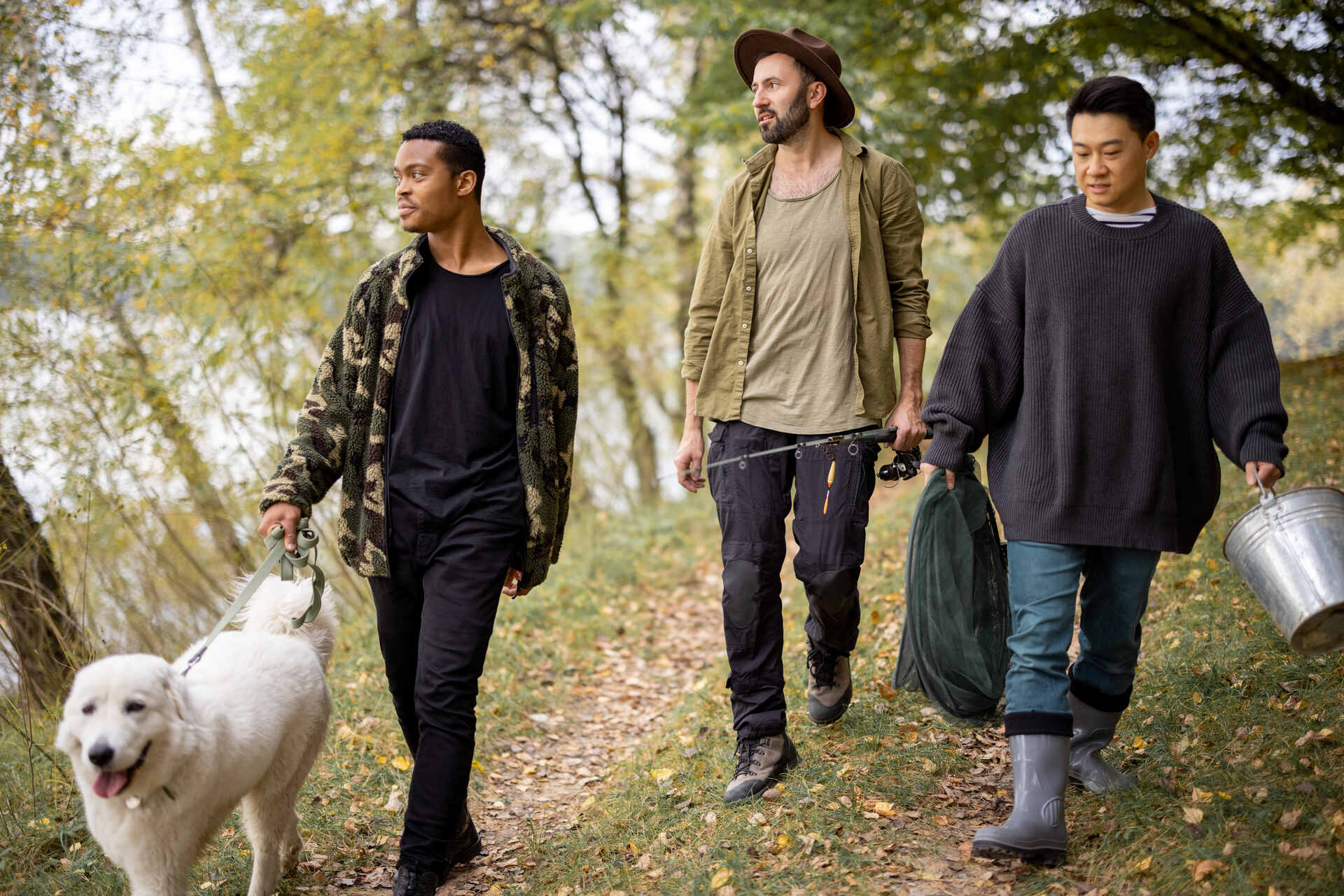 Three men walking a dog through a forest trail