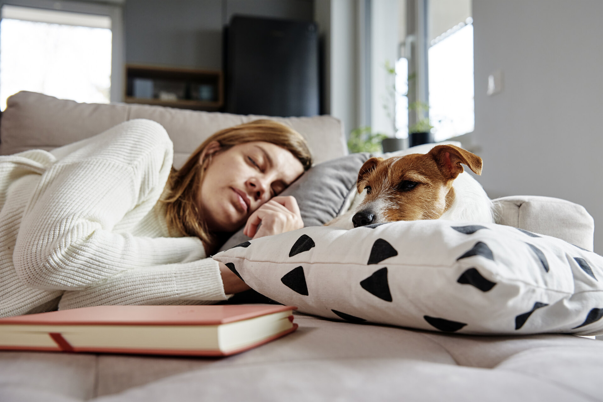 A woman sleeping next to a dog at home