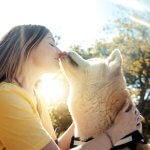 A woman kissing her dog on a sunny day