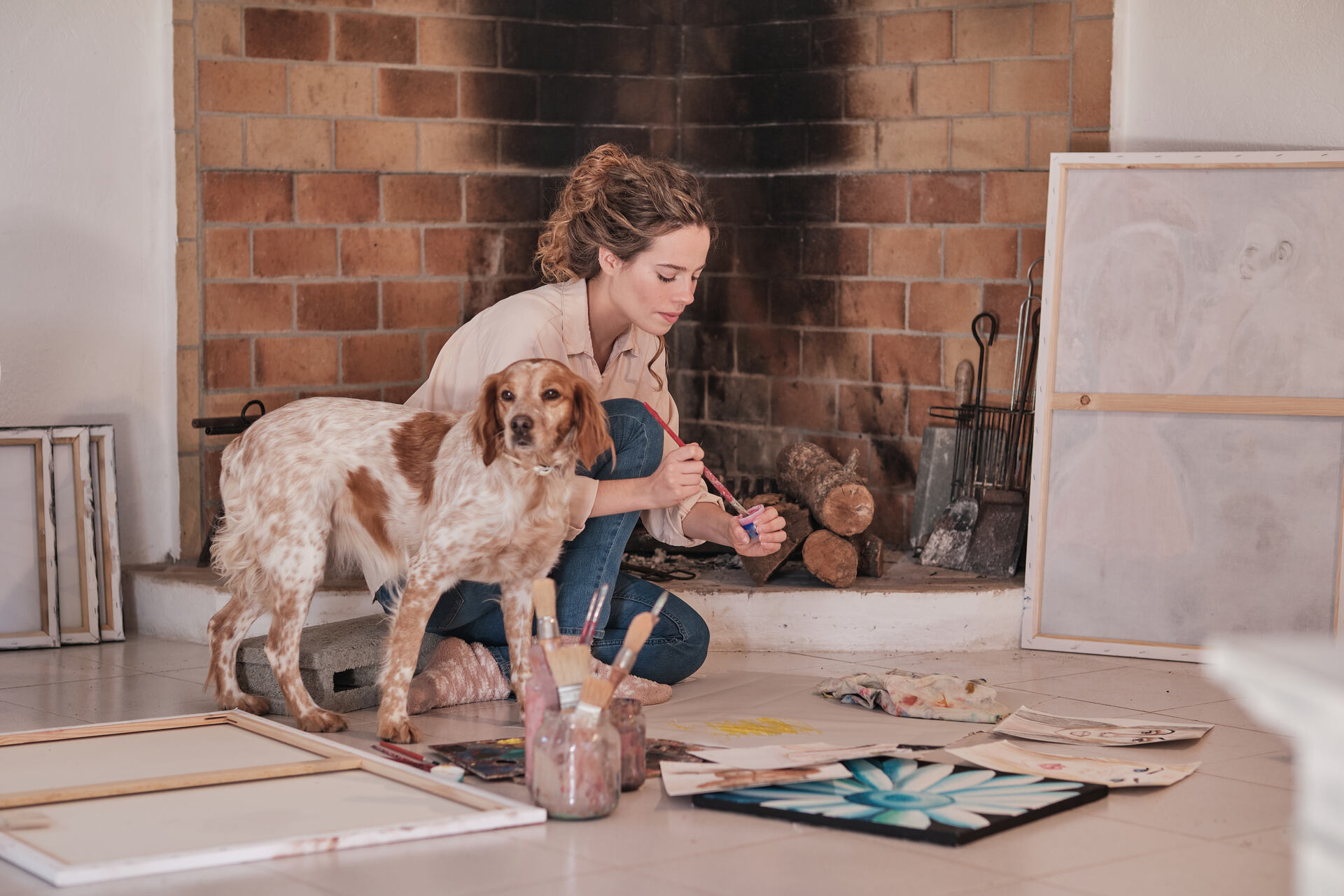 A woman painting with her dog indoors