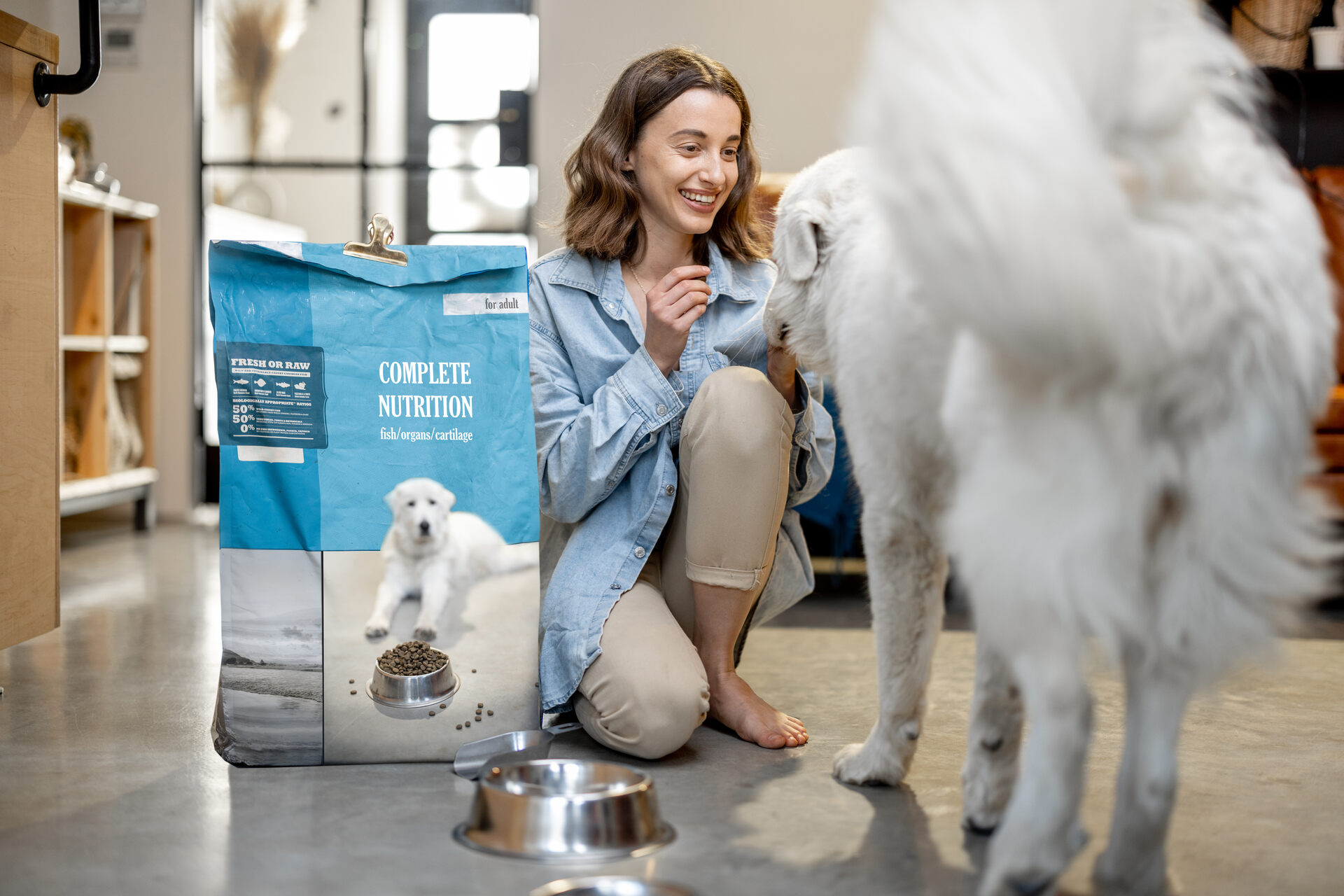 A woman feeding her dog from a commercial dog food packet