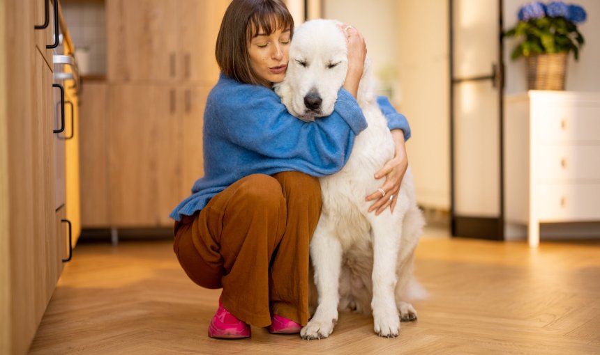 A woman hugging her anxious dog indoors