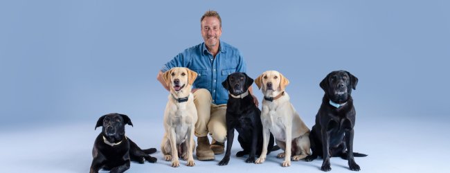 UK adventurer Ben Fogle kneeling with 4 Labrador dogs wearing Tractive GPS trackers