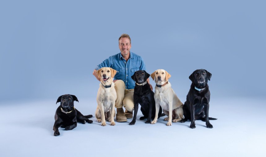 UK adventurer Ben Fogle kneeling with 4 Labrador dogs wearing Tractive GPS trackers