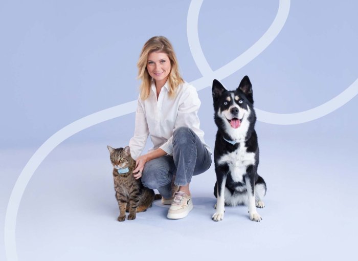 Sandrine Arcizet poses with a cat and dog wearing Tractive GPS trackers.