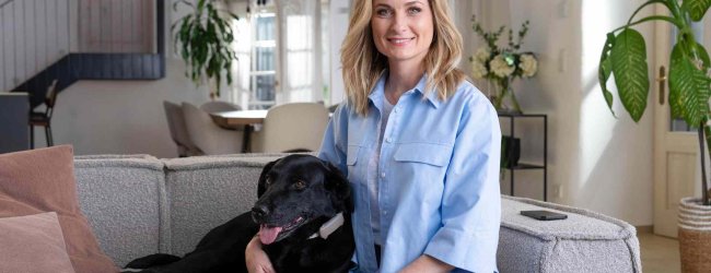 A woman sitting with a dog that's wearing a Tractive device