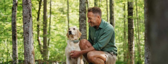 A man training a dog that's wearing a Tractive GPS tracker