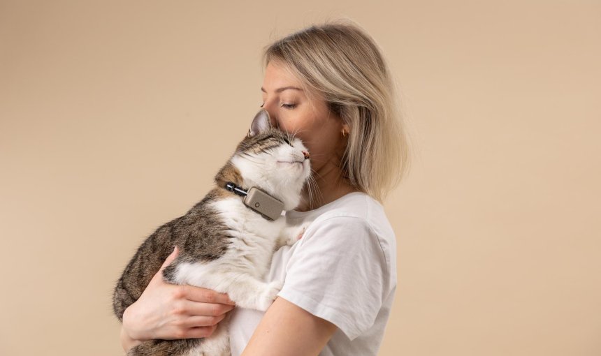 A woman hugging a cat that's wearing a Tractive GPS tracker