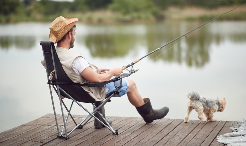 Mann angelt an einem Steg mit kleinem Hund