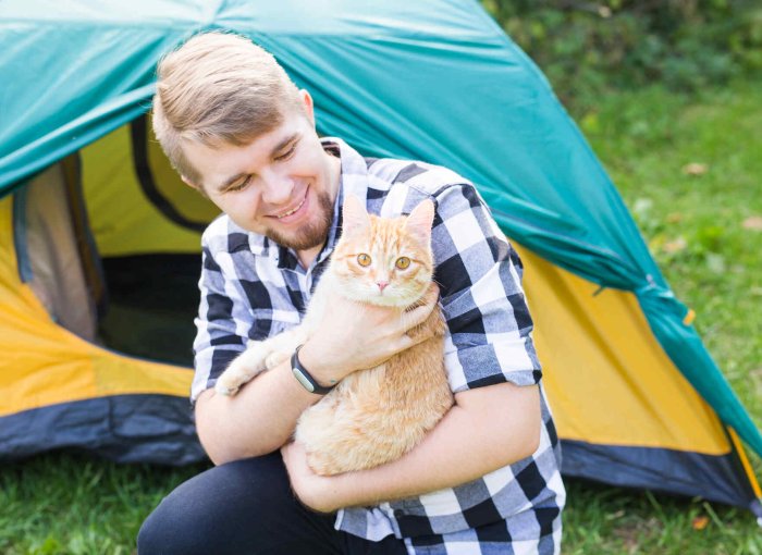 Mann beim Camping mit seiner Katze am Arm