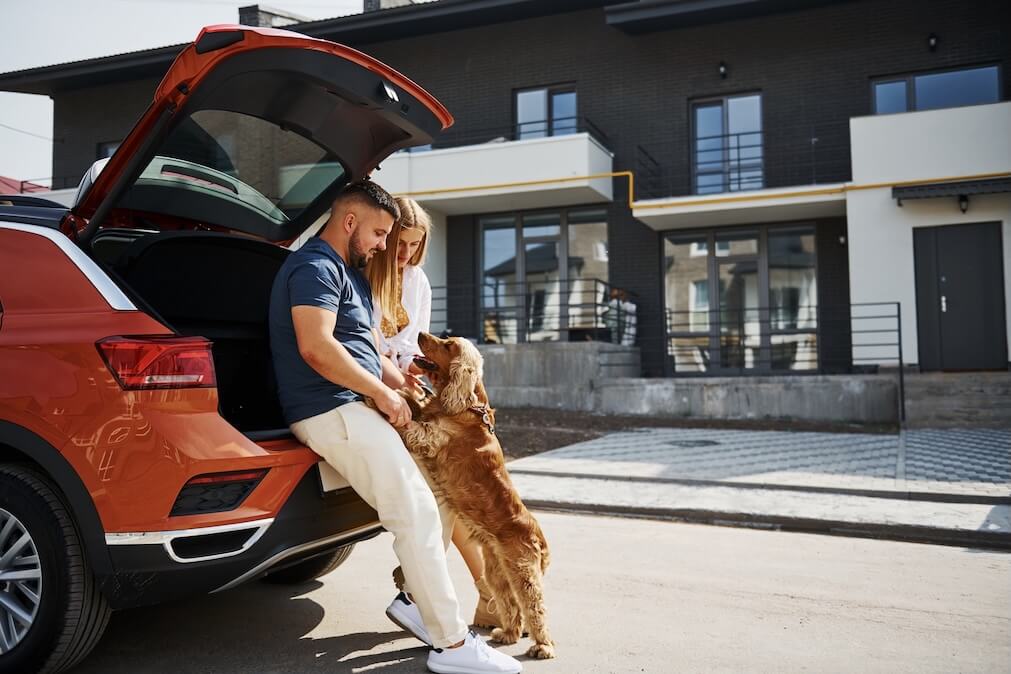 Hund mit Besitzer an Auto gelehnt