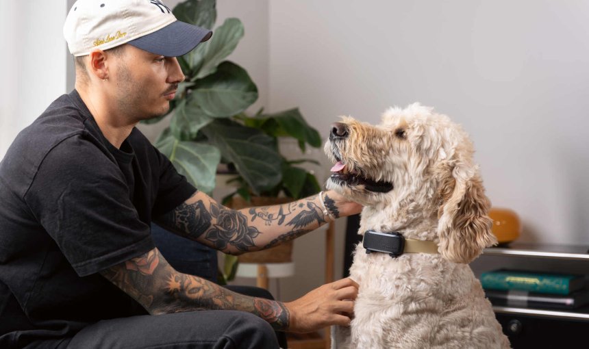 A man sitting with a dog wearing a Tractive GPS & Health tracker