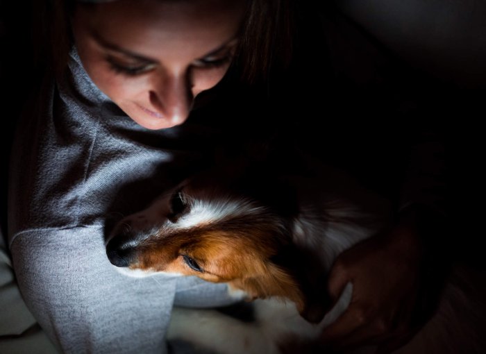 A woman comforting her dog at nighttime
