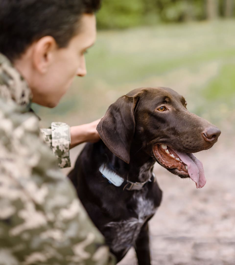 Hombre con camuflaje sujetando a su perro de caza